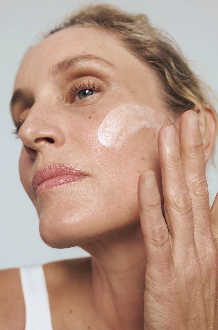 Woman applying Rest Religion moisturizer to her cheek